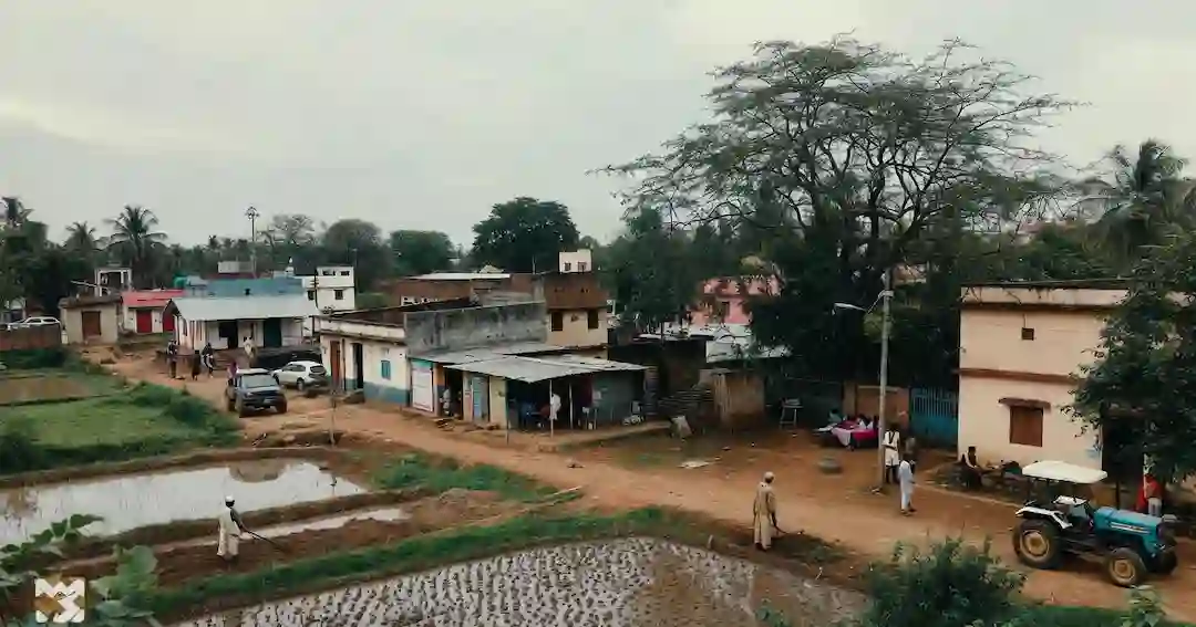 Rural India agriculture Directory Wide view of rural India village with houses, trees, roads, and everyday community activity